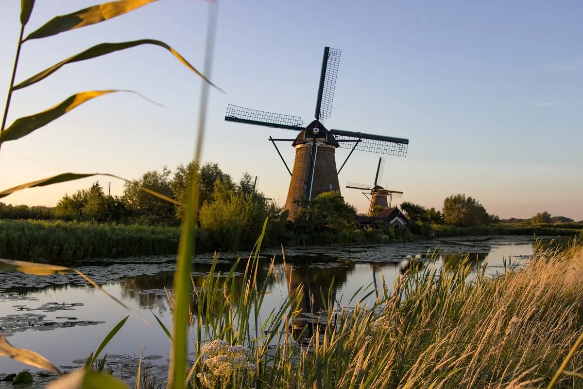 Un moulin aux couleurs du coucher de soleil avec son reflet dans l'eau