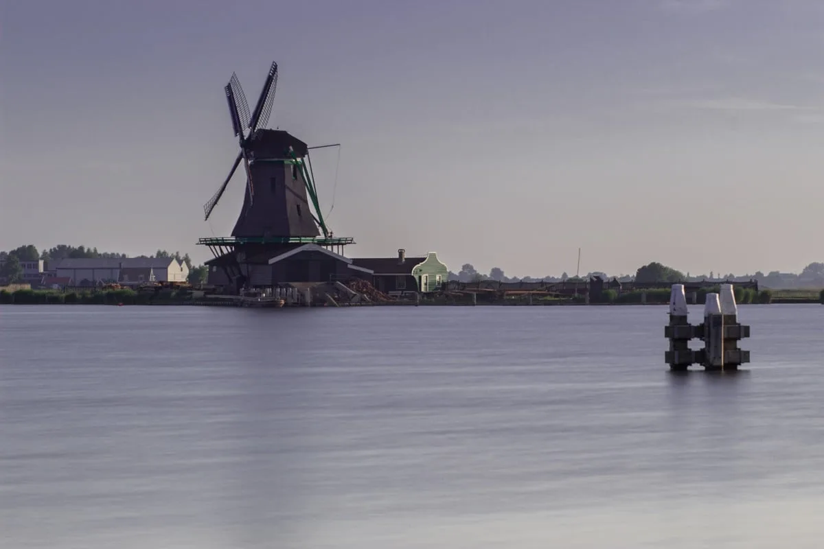 Moulin à vent près de l'eau aux premières lueurs de la journée