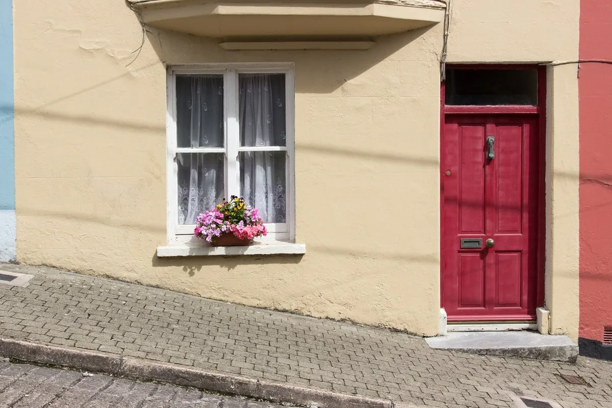 Une maison avec une porte rouge dans une rue très pentue