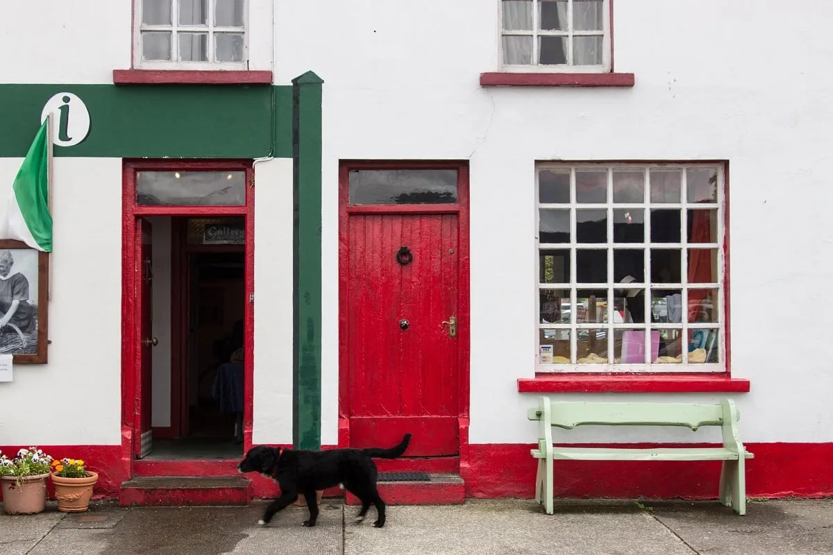 Façade rouge et blanche avec un chien qui passe