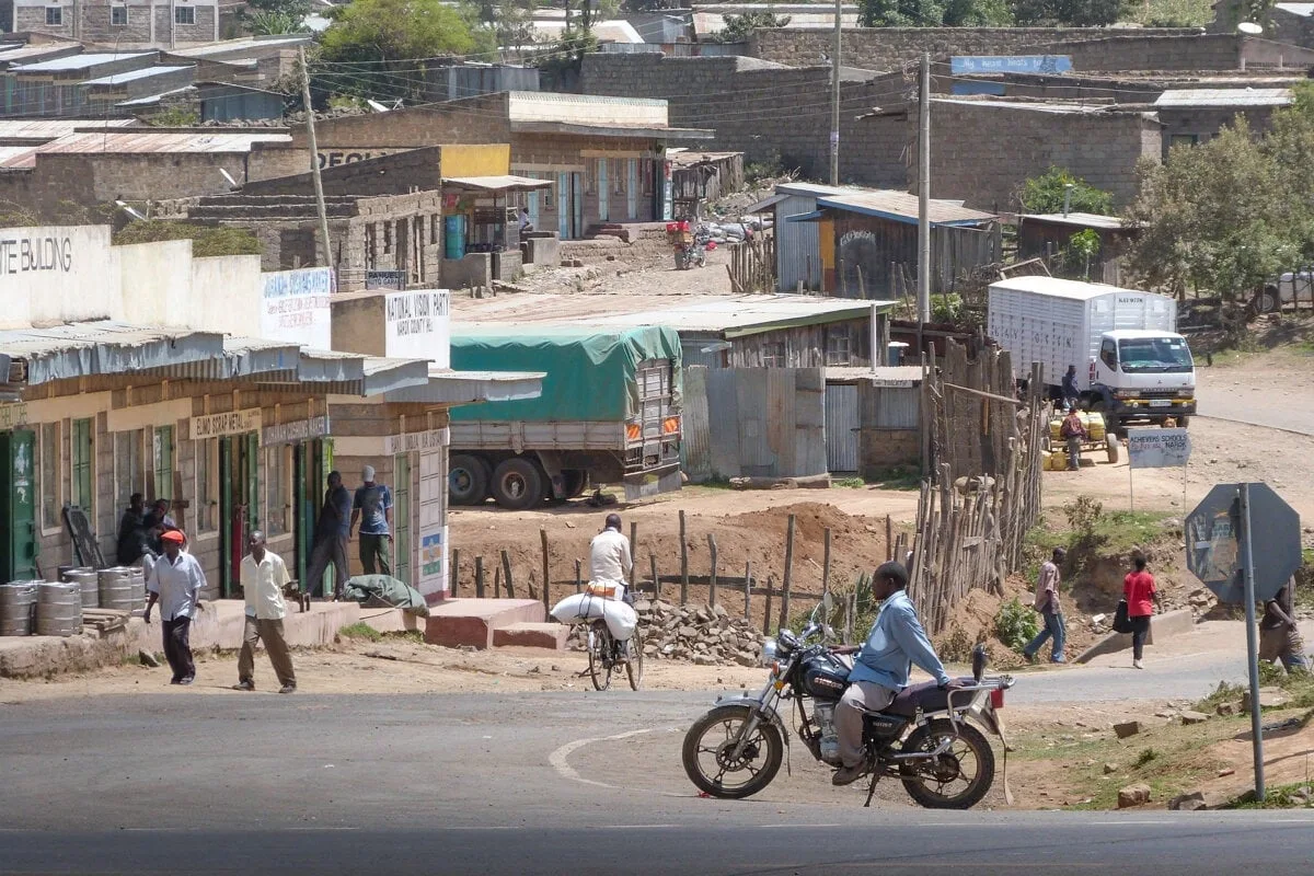 Traversée d'un village avec des habitations, des passants et une moto