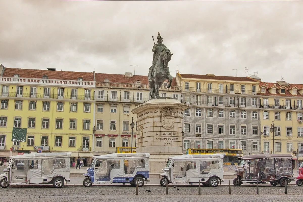 Des tuk tuk garés sur une place au pied d'une statue