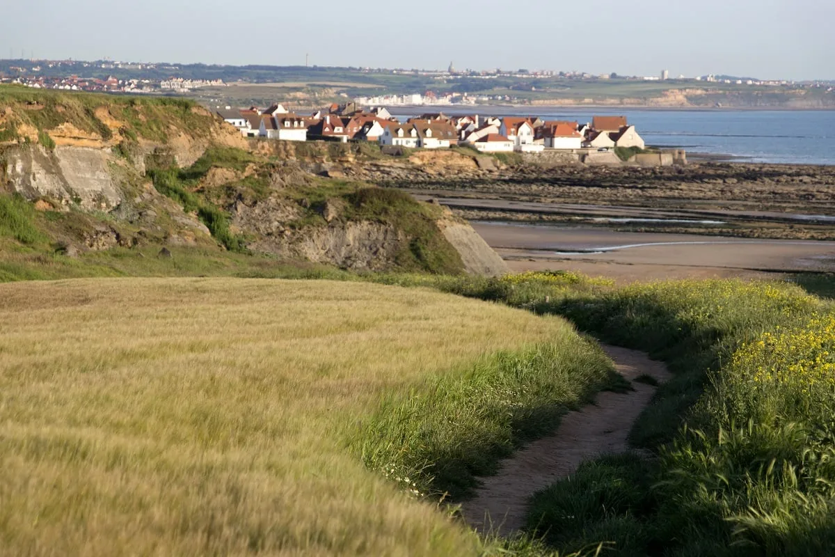 Sur un chemin de randonnée avec un village au fond au bord de la mer