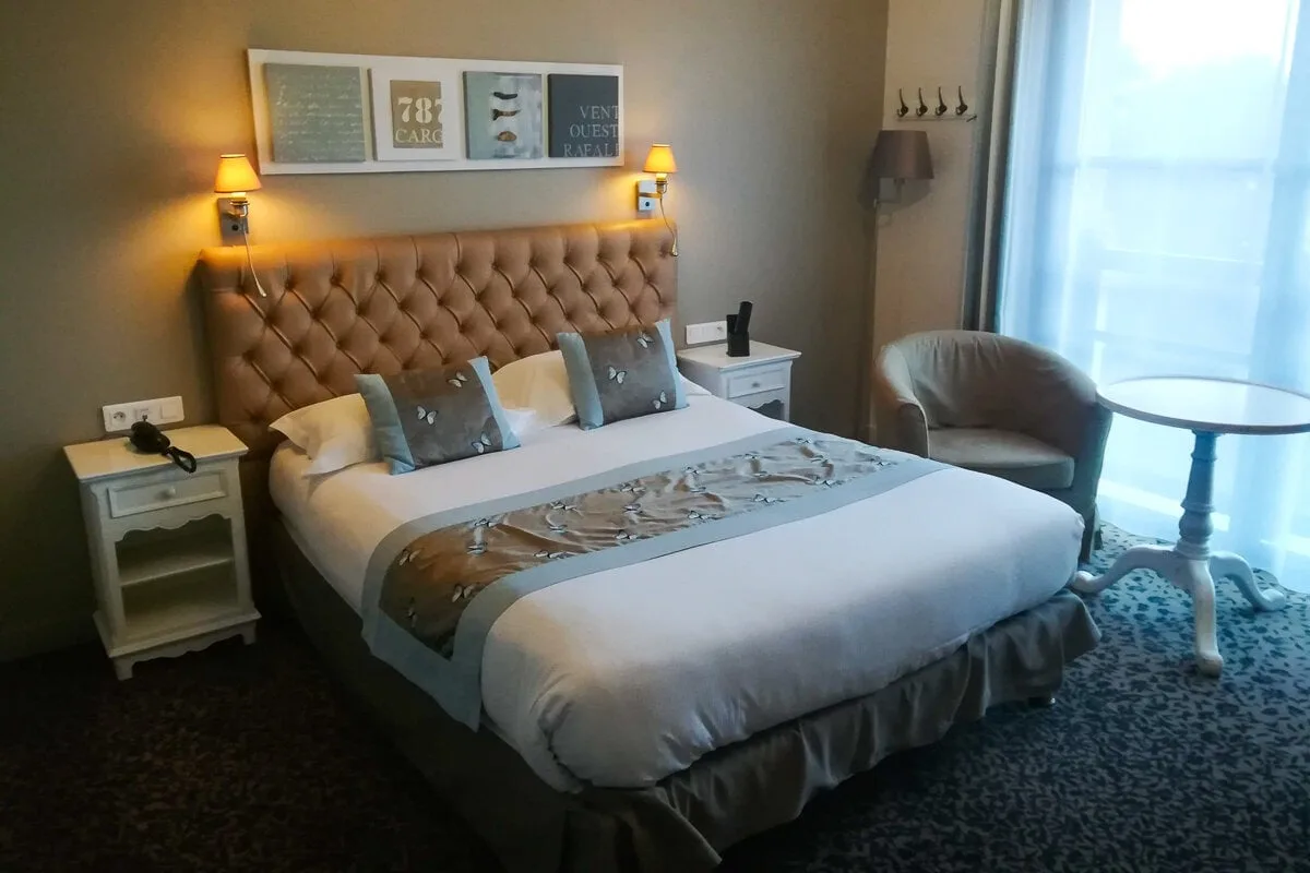 Chambre dans les jardins d'Hardelot (grand lit, cadres au mur et lampes de chevet allumées)