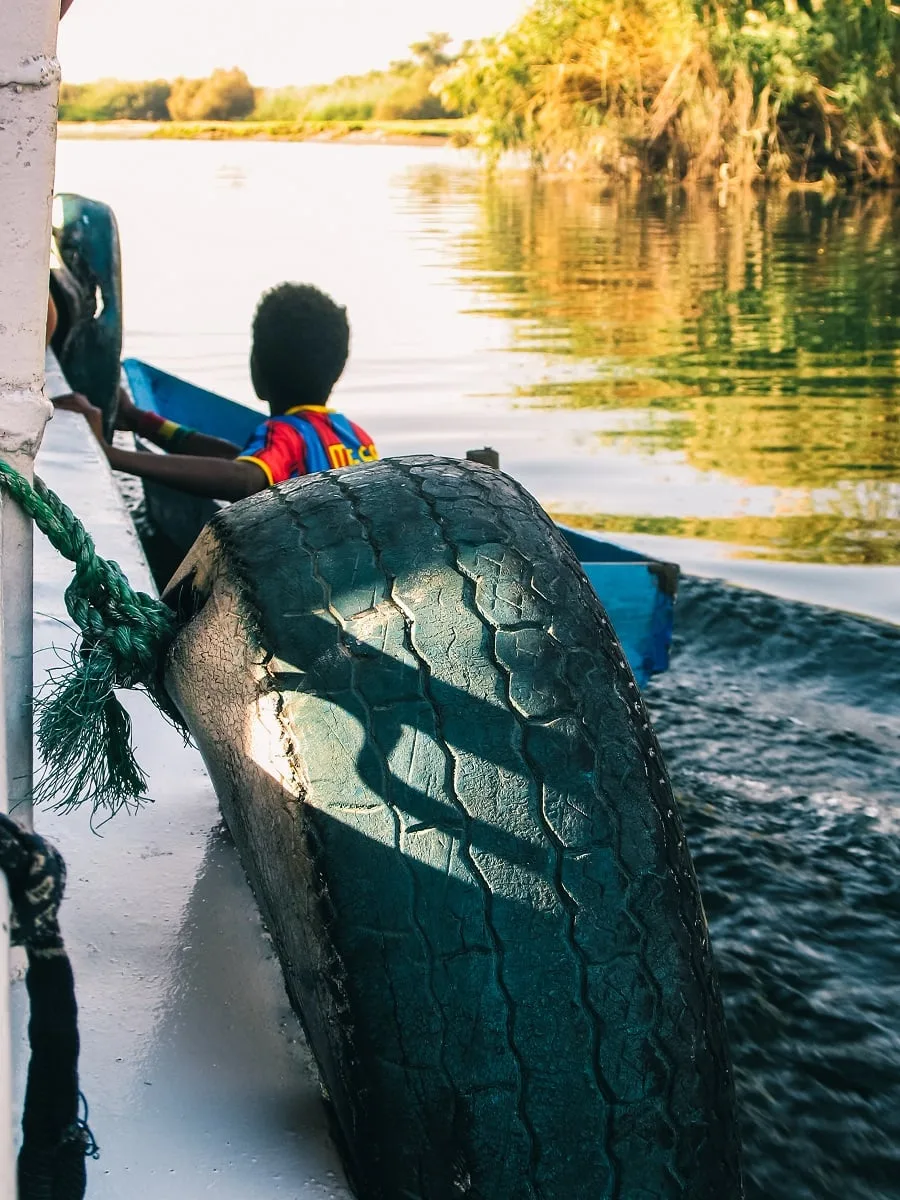 Enfant près d'une felouque sur le Nil à Assouan