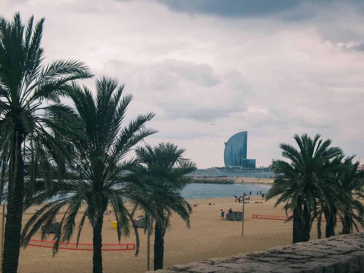Plage avec palmiers et un hôtel au fond