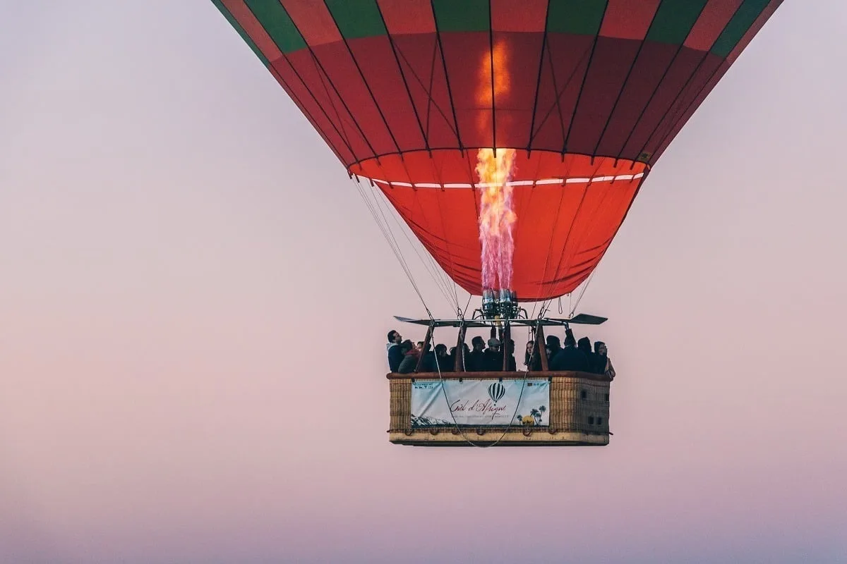 Flamme dans une montgolfière dans les airs avec la nacelle et des personnes à l'intérieur