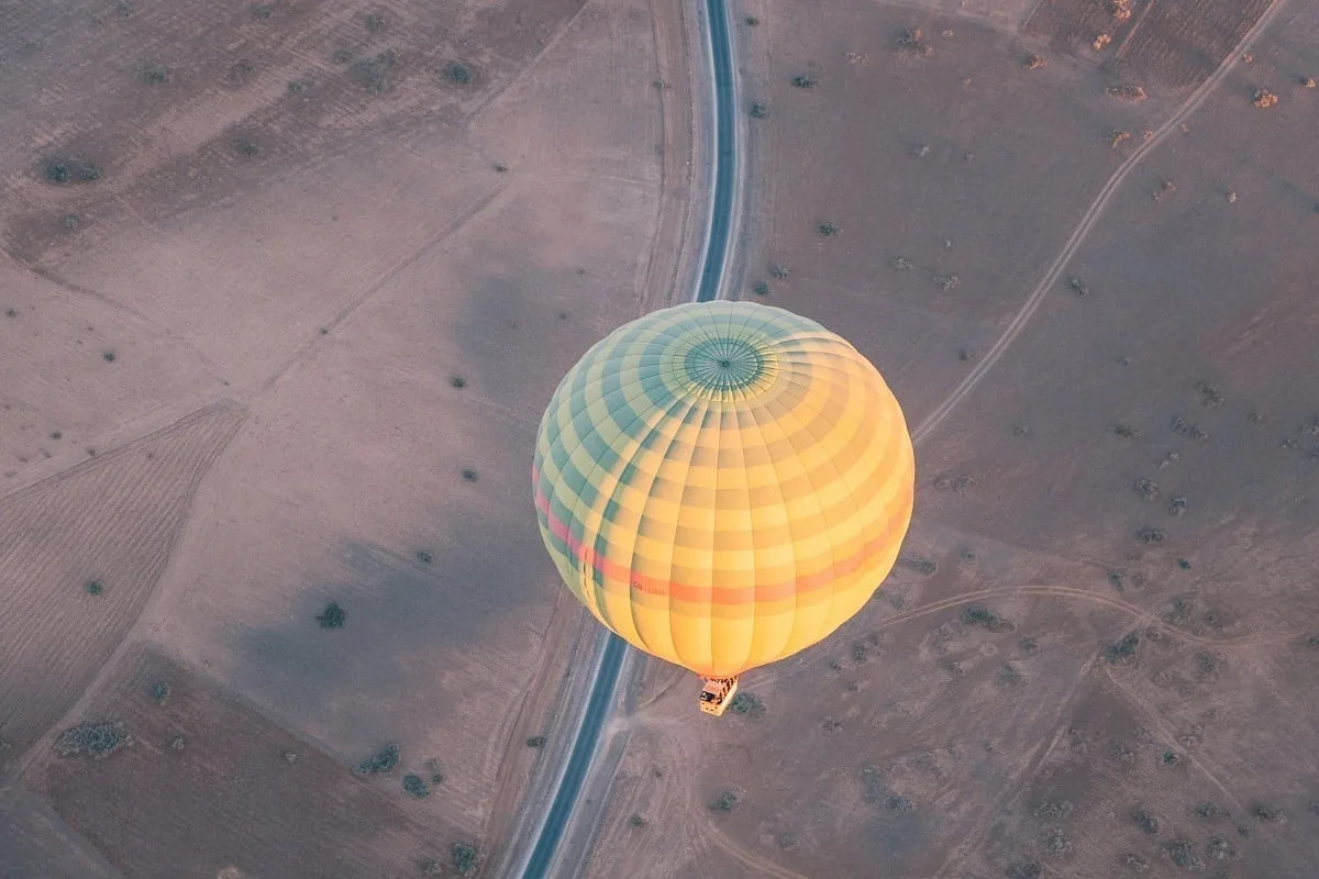Vue d'une montgolfière du dessus, et les champs arides et la route en dessous