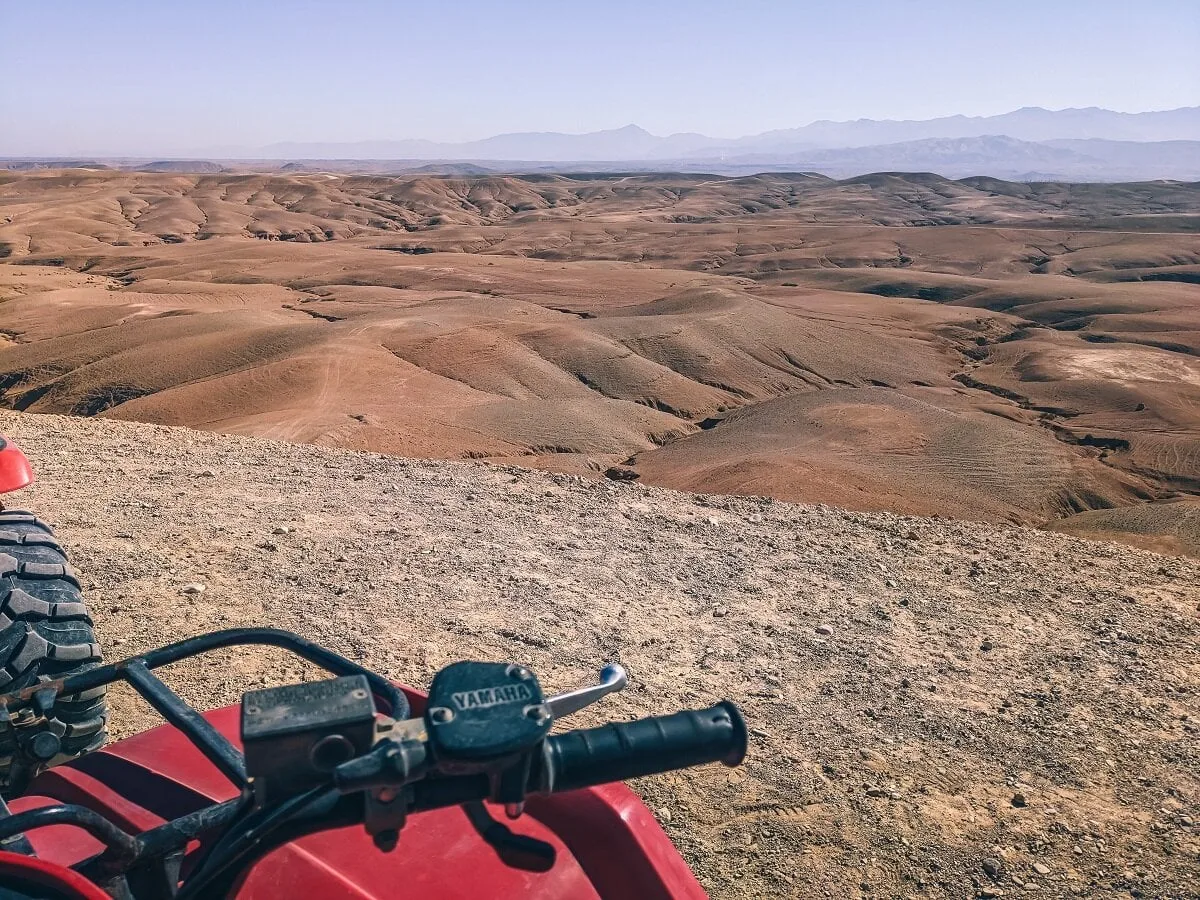 Paysages vallonnés dans le désert d'Agafay, avec un guidon de quad au premier plan