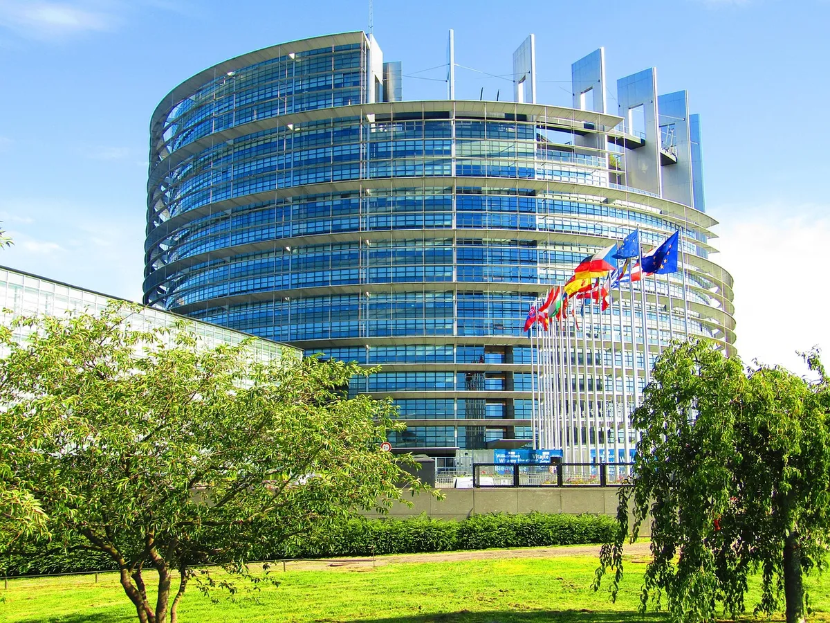Bâtiment moderne en verre avec drapeaux colorés et verdure environnante