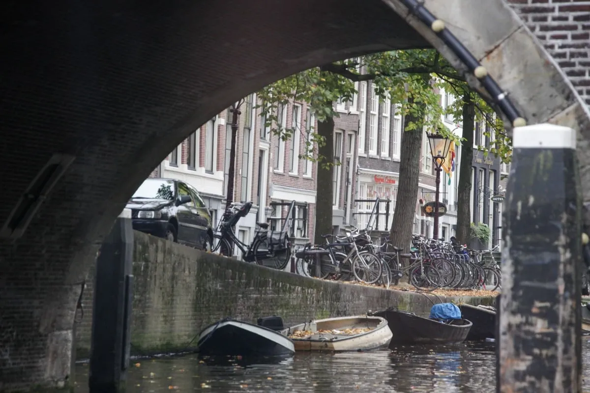 Vue sous une arche de pont sur un canal avec barques et vélos