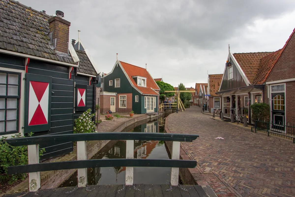 Petit pont blanc enjambant un canal bordé de maisons colorées