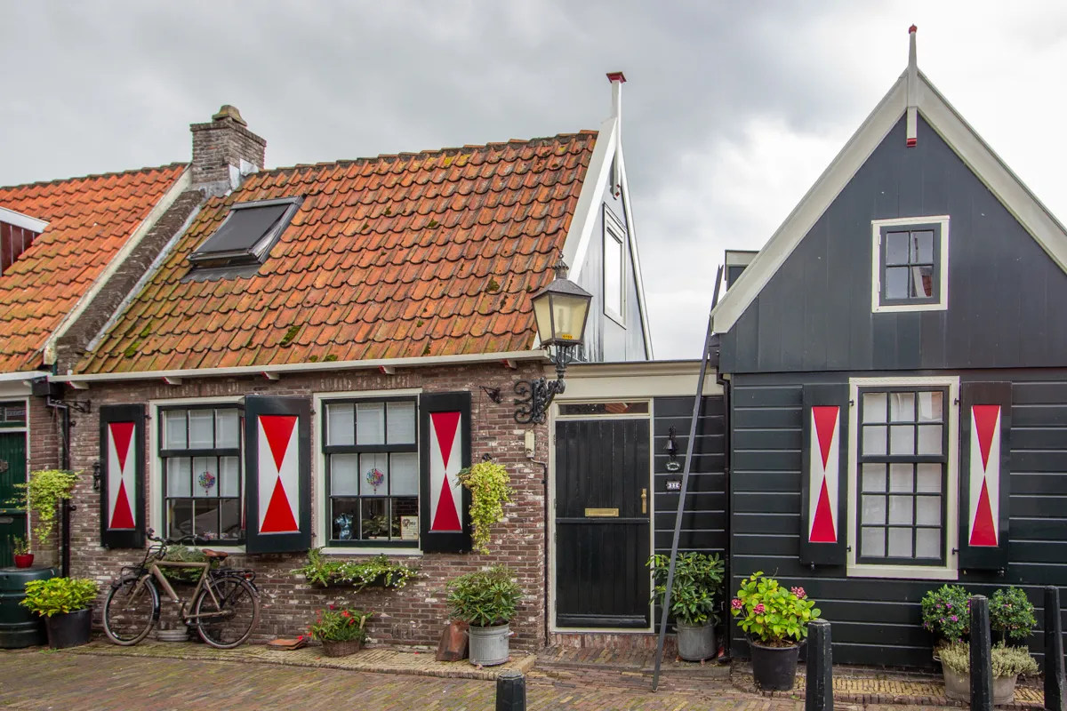 Deux maisons traditionnelles aux volets rouges et blancs avec vélo