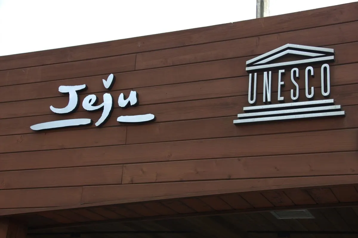 Panneau en bois avec logo Jeju et symbole UNESCO en blanc