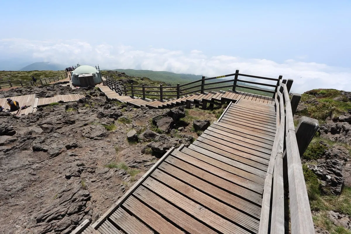 Passerelle en bois sinueuse sur terrain volcanique au-dessus des nuages