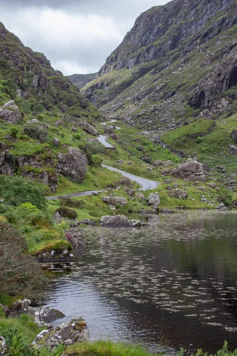 Route sinueuse serpentant dans un col montagneux avec lac au premier plan
