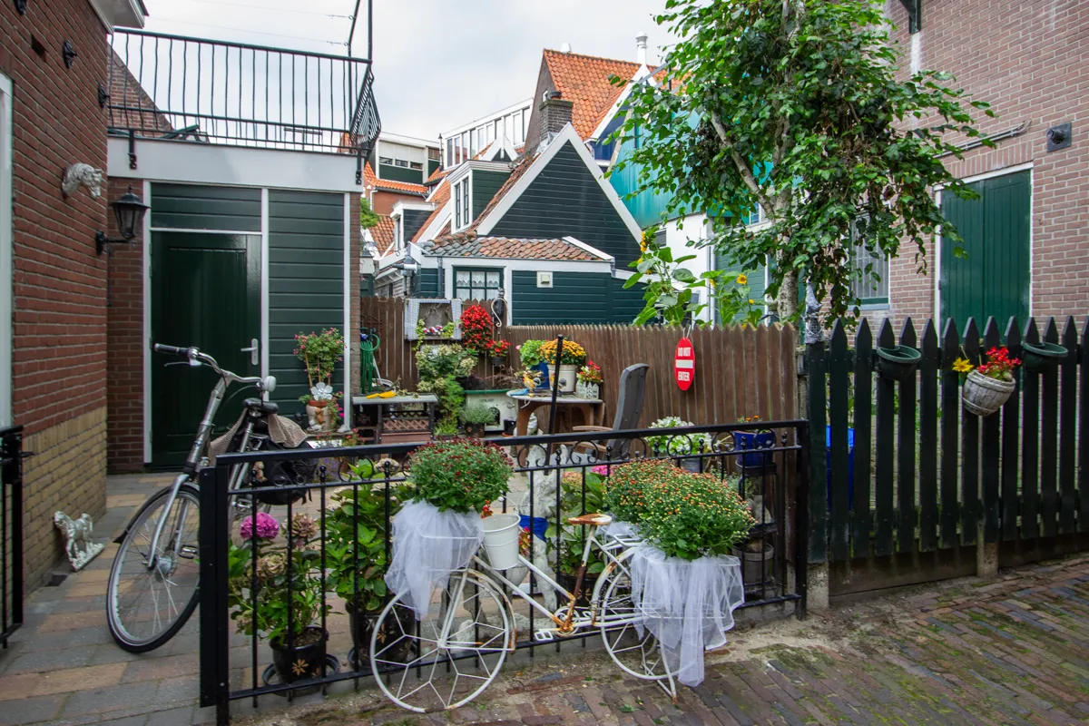 Vélo blanc décoré de fleurs devant une cour fleurie