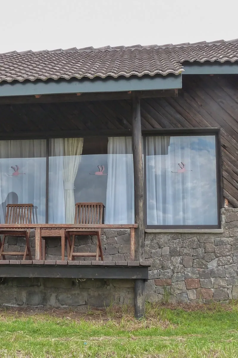 Terrasse en bois avec chaises, bungalow en pierre et rideaux blancs