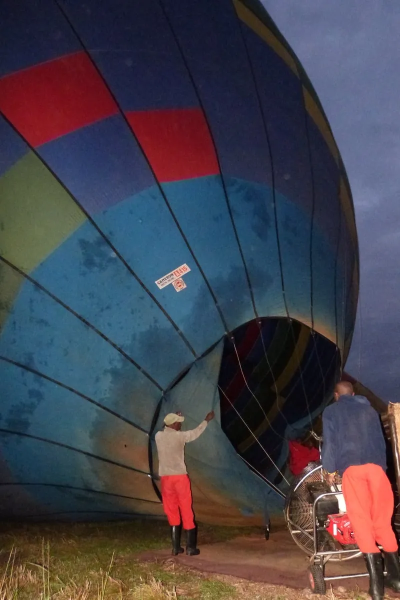 Équipe au sol gonflant une montgolfière à l'aube