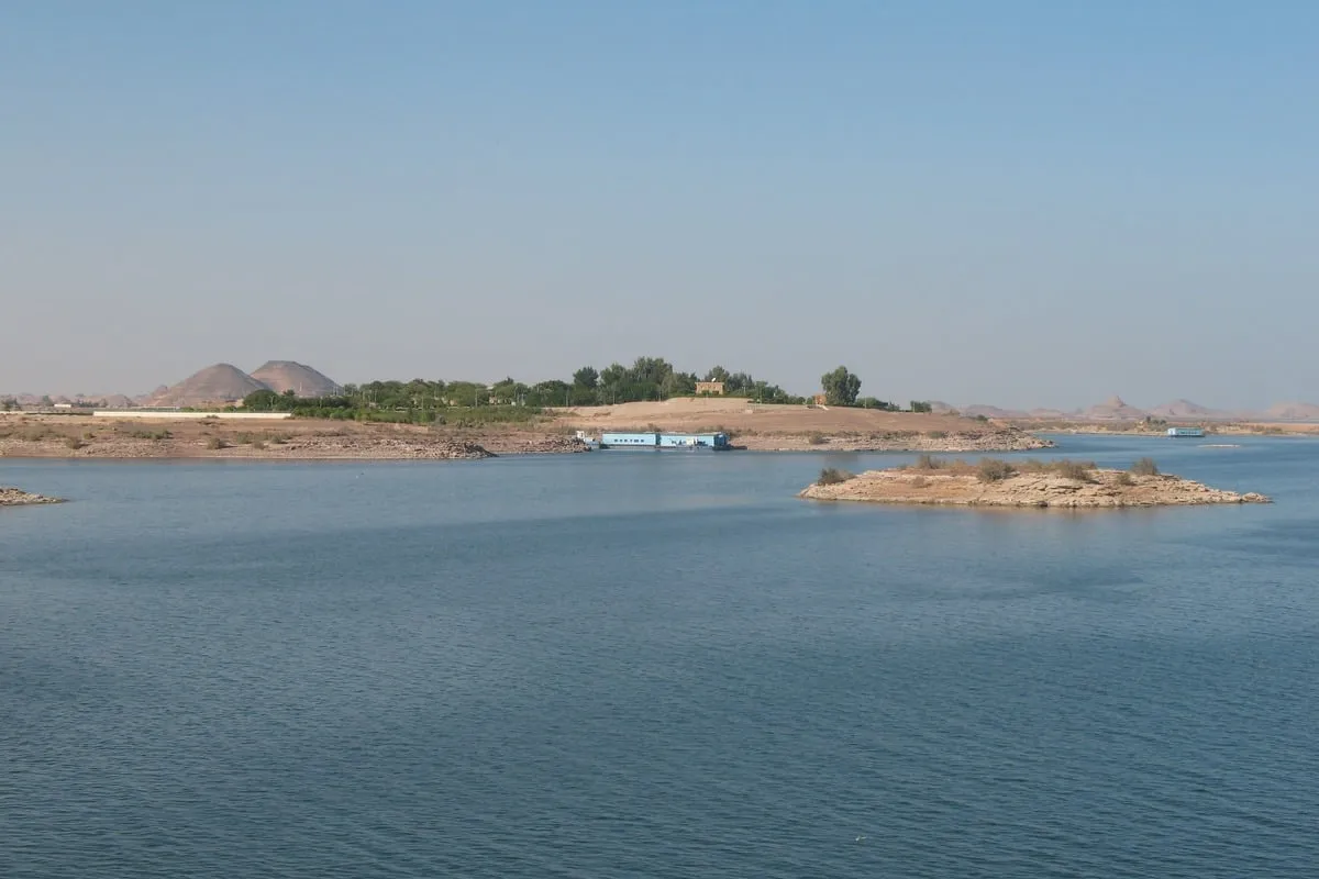 îlots rocheux, barge bleue et collines arides en arrière-plan