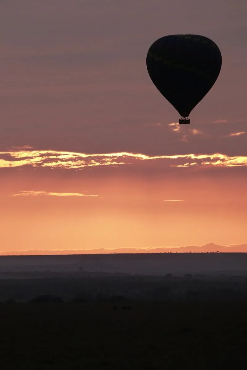 Silhouette d'une montgolfière au lever du soleil sur horizon nuageux
