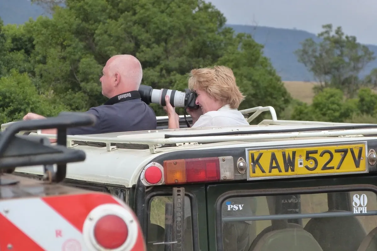 Deux photographes debout dans un 4x4 toit ouvert, appareils photo en main