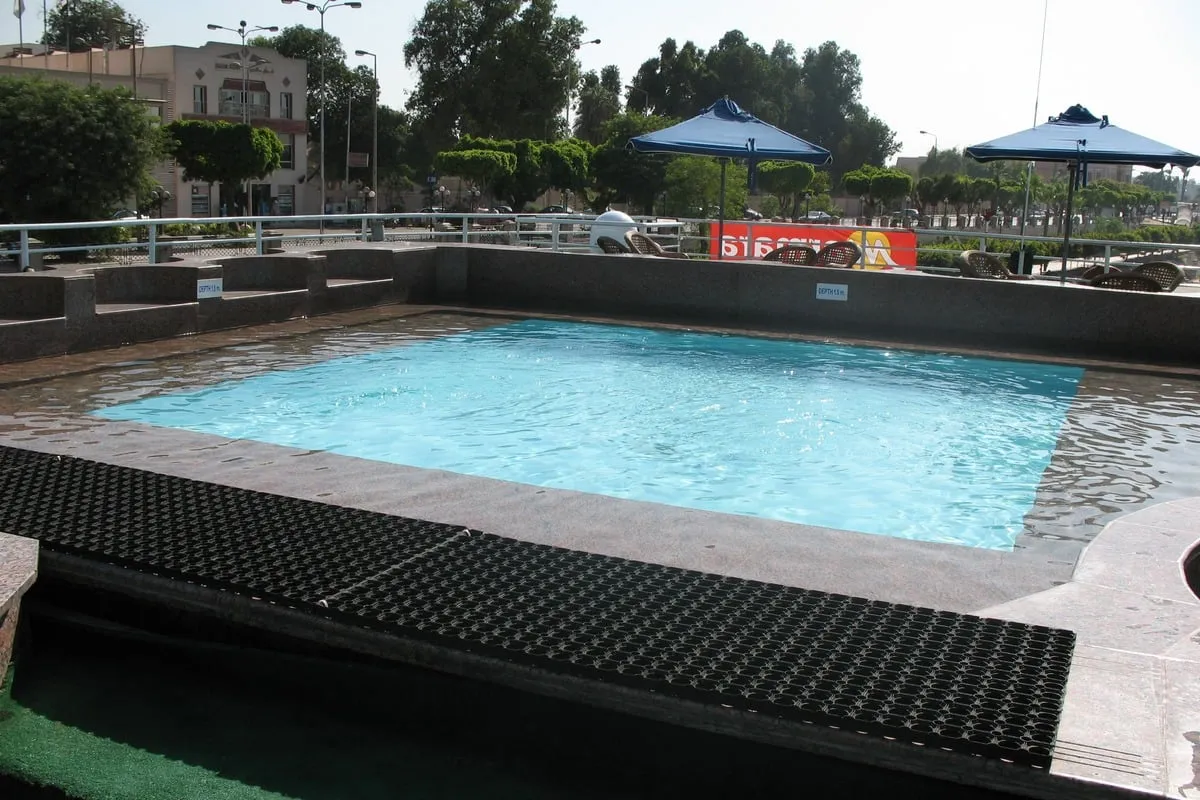 Petite piscine extérieure rectangulaire entourée de parasols bleus
